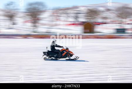 ZHANGJIAKOU, CHINA - 5. FEBRUAR 2022 - Touristen erleben Schneemobile im touristischen Kulunnur-Gebiet in Zhangjiakou, der nordchinesischen Provinz Hebei, Fe Stockfoto