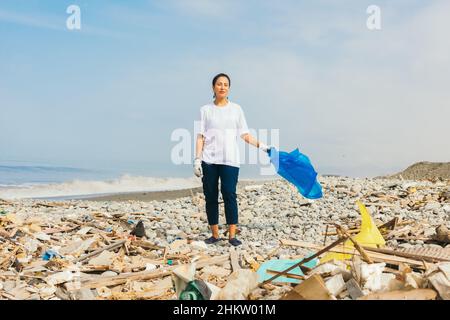 Junge Freiwillige am Strand voller Müll Stockfoto