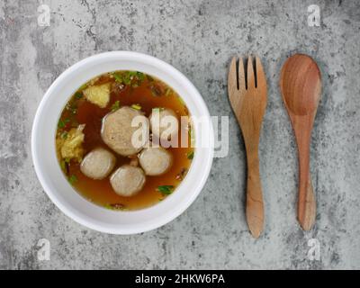 Draufsicht auf Fleischbällchen in einer weißen Schüssel mit Holzlöffel und Gabel. Stockfoto