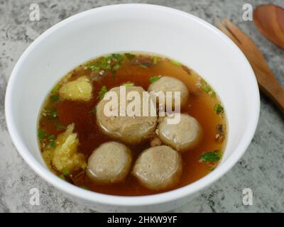 Fleischbällchen in einer weißen Schüssel mit einem Holzlöffel und einer Gabel. Stockfoto