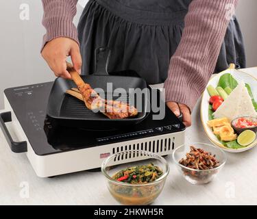 Kochvorgang in der Küche: Gegrillte Sate Lilit (Satay Lilit), traditionelle balinesische Hackfleisch Meeresfrüchte oder Huhn Satay mit Bambus oder Lemongrass Skew Stockfoto