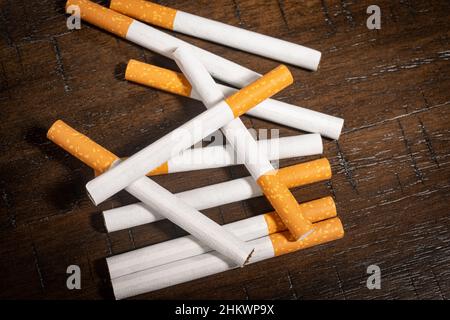 Ein kleiner Stapel loser Zigaretten sitzt auf einem Holztisch. Stockfoto