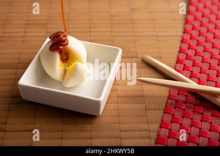 Mini-Mochi-Eiscreme mit Karamell (cäceta). Traditionelles japanisches Dessert aus Reismehl. Nahaufnahme auf Bambusoberfläche. Stockfoto