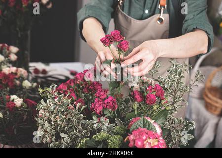 Florist machen Geschenk Sträuße. Anmutige weibliche Hände machen einen schönen Strauß. Floristen-Arbeitsplatz. Konzept für kleine Unternehmen. Blumen und Accessoires. Stockfoto