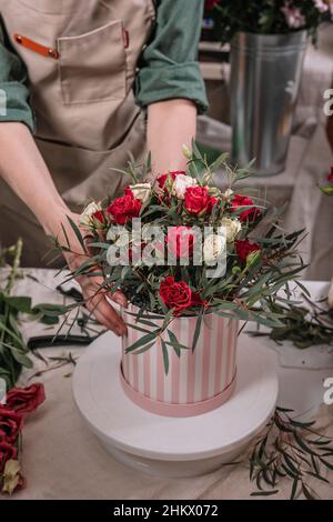 Florist machen Geschenk Sträuße in Hutboxen. Anmutige weibliche Hände machen einen schönen Strauß. Floristen-Arbeitsplatz. Konzept für kleine Unternehmen. Blumen und Zugang Stockfoto