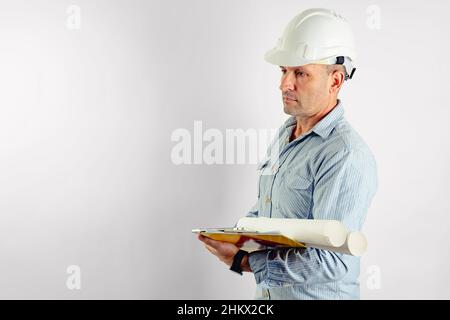 Ein männlicher Vorarbeiter mittleren Alters in einem hellen Hemd und einem weißen harten Helm. Isoliertes Porträt auf weißem Hintergrund. Speicherplatz kopieren. Stockfoto für Männer Stockfoto