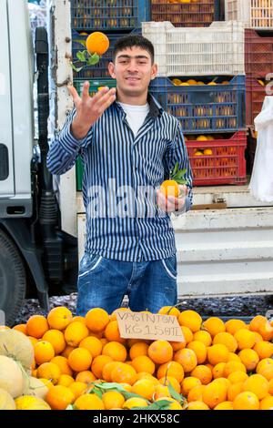 Ein türkischer Gemüsehändler, der Orangen auf dem Kas Freitagsmarkt verkauft. KAS ist ein Dorf am Mittelmeer in der Türkei. Stockfoto