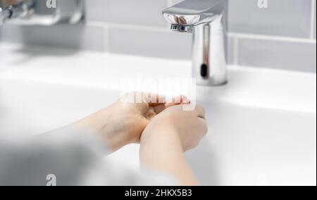 Aus nächster Nähe wäscht das Kind seine Hände im Badezimmer. Stockfoto