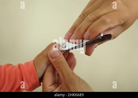 Womans Hand hält Kinder Hand geschnitten Kleinkind Fingernagel mit Clippers Stockfoto