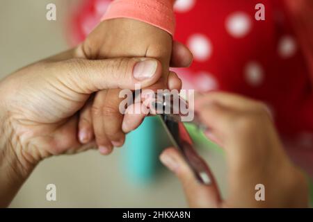 Womans Hand hält Kinder Hand geschnitten Kleinkind Fingernagel mit Clippers Stockfoto