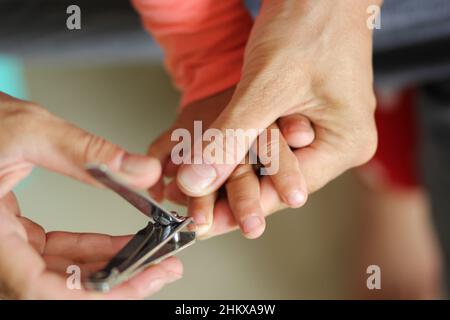 Womans Hand hält Kinder Hand geschnitten Kleinkind Fingernagel mit Clippers Stockfoto