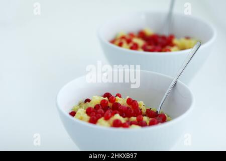 Two bowls with homemade healthy maize porridge with red currant on the white table Stockfoto