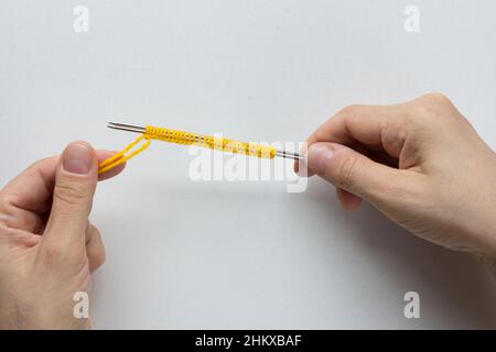 Gießen Sie auf. Stricken. Auf dem weißen Hintergrund die Maschen auf den Nadeln stricken. Draufsicht. Stockfoto
