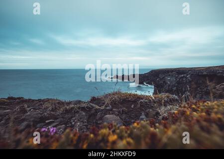 Basaltfelsen und Klippen auf Hellnar in Island an einem bewölkten Tag im Sommer. Majestätische Aussicht über die Klippen auf Island Stockfoto