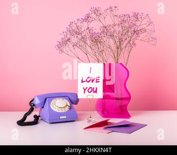 Valentinstag-Konzept. Karte mit den Worten Ich liebe dich. Liebeserklärung. Retro-Telefon, Vase mit getrockneten Blumen, Umschläge mit Liebesbriefen am Tisch. Hochwertige Fotos Stockfoto