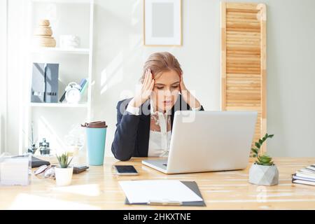 Geschäftsfrau mit Kopfschmerzen im Büro Stockfoto