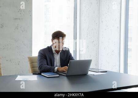 Viel beschäftigte, selbstbewusste, reife Geschäftsführerin, die am Computer im Büro arbeitet Stockfoto