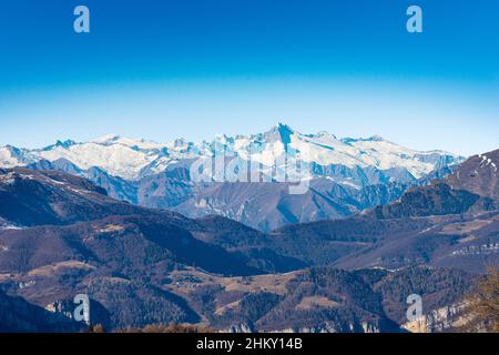 Die Bergkette des Monte Baldo, das Etschtal und der Nationalpark Adamello Brenta mit dem Gipfel des Care Alto von der Lessinia-Hochebene aus gesehen. Italien. Stockfoto