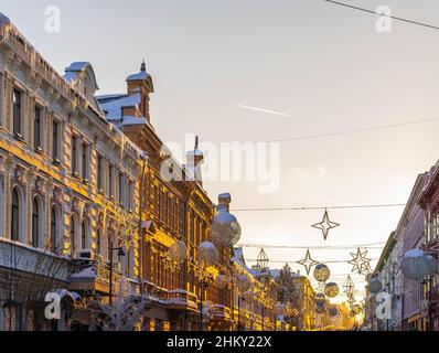 Eine Straße mit alten Häusern bei Sonnenuntergang. Das Herz der Altstadt. Eine Attraktion für Touristen und Einheimische. Reflexion des Sonnenlichts an den Wänden der Häuser Stockfoto