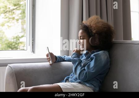 Happy Black Teenager-Mädchen in kabellosen Kopfhörern Musik hören Stockfoto