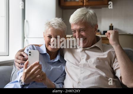 Fröhliches, aufgeregtes Seniorenpaar überraschte mit guten, überraschenden Nachrichten Stockfoto
