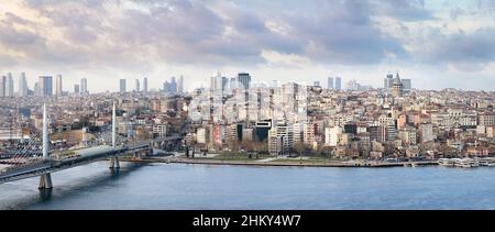 Ein Panoramablick auf Istanbul mit dem Galata-Turm und der Metro-Brücke über das seidige Wasser des Goldenen Horns bei bewölktem Wetter. Panoramafoto von Stockfoto