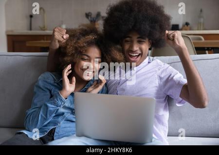 Aufgeregt überrascht afrikanisches Teenager-Paar mit Laptop Stockfoto