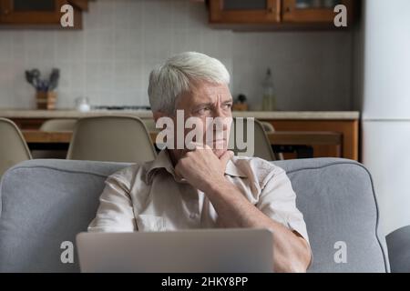 Nachdenklich gestresst reifen 70s Mann mit Laptop-Computer Stockfoto