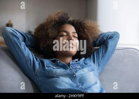 Ruhige, schlafende, afrikanische Teenager-Mädchen, die sich auf einem bequemen Sofa entspannen Stockfoto