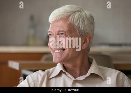 Glücklicher älterer 60s Mann, der in tiefen guten Gedanken wegschaut Stockfoto