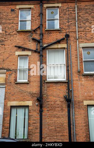 Nahaufnahme von Dachrinnen und Abfallrohren aus dem Bad, der Küche und der Wäsche eines alten Backsteinhauses. Stockfoto