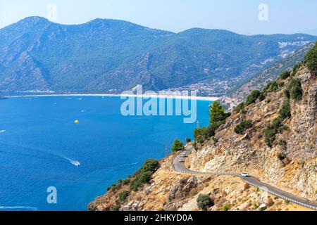 Kurvige Kurve der Bergautobahn mit blauem Himmel und Meer auf einem Hintergrund. Fethiye Oludeniz Strandblick vom Hügel, Türkei. Stockfoto