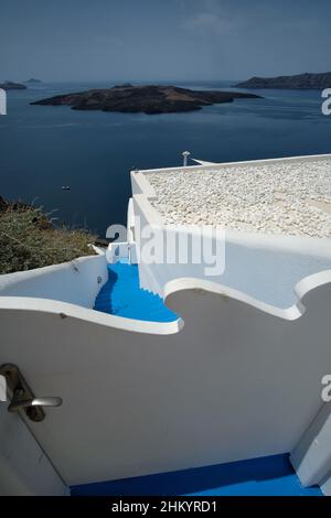 Santorini, Griechenland - 7. Mai 2021 : Eine Tür und eine Treppe führen zu einem Wohnhaus mit Blick auf die Ägäis und den Vulkan von Santorini Stockfoto
