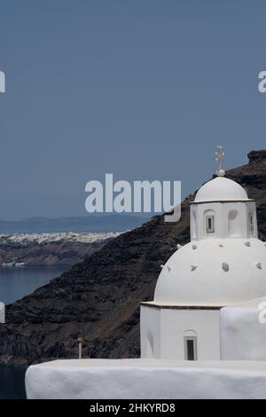 Tolle Aussicht von einer weißgetünchten orthodoxen Kirche und dem berühmten Dorf Oia im Hintergrund Stockfoto