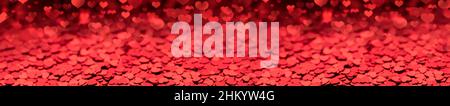 Roter Hintergrund von kleinen Herzen, langes Panorama-Layout unfokusiert. Stockfoto