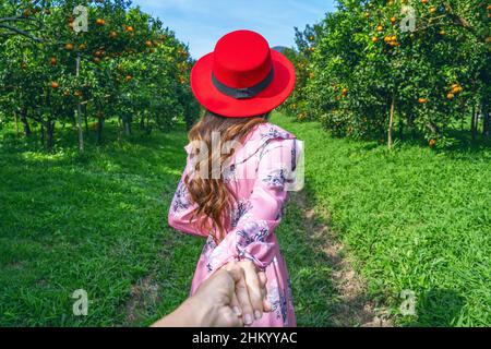 Weibliche Touristen halten die Hand des Mannes und führen ihn in den orangefarbenen Garten. Stockfoto