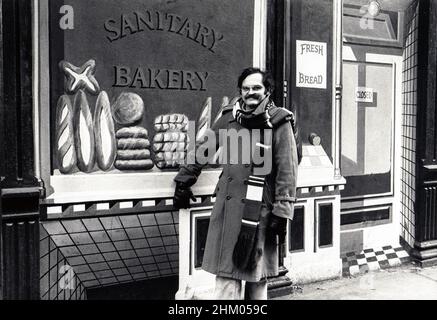 Trompe L'Oiel-Künstler Richard Haas steht vor einer seiner Kreationen. Die Kante, auf die er sich stützt, ist eine flache Oberfläche auf seinem Wandbild. 1977 in Soho, New York City. Stockfoto