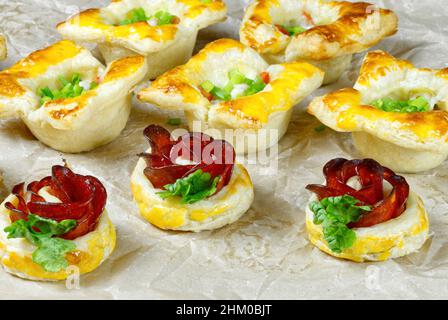 Frisches, hausgemachtes Gebäck. Mischung aus Blätterteig und Vorspeisen. Rosafarbter Pfefferoni-Kuchen. Gebäck mit Salami. Stockfoto