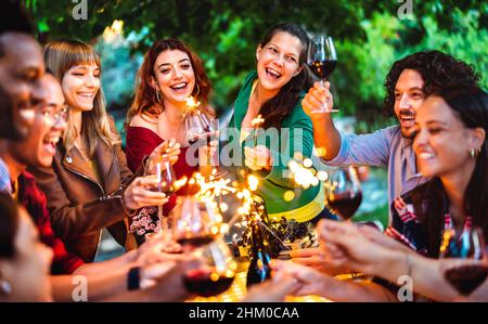 Glückliche Freunde, die Spaß mit Feuer funkelt beim Toasten Rotwein - Junge Millennial Menschen Camping auf Sommer Picknick Grillparty in der Nachtstimmung - Y Stockfoto