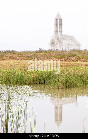 Ein Paar in der Ferne an der wunderschönen weißen Kirche, die sich in einem kleinen Teich widerspiegelt Stockfoto