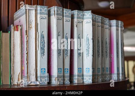 Die Sammlung des Korans und der Hadith in der Bibliothek der Moschee, die an der Wand gesäumt ist, steht aufrecht, vertikal und vertikal. Stockfoto