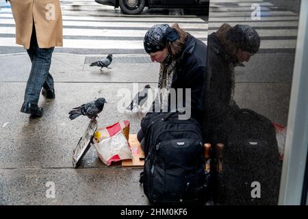 2. Februar 2022, New York, NY, USA: 2. Februar, 2022. Obdachlose und Tauben vor einem Starbucks. (Bild: © John Marshall Mantel/ZUMA Press Wire) Stockfoto