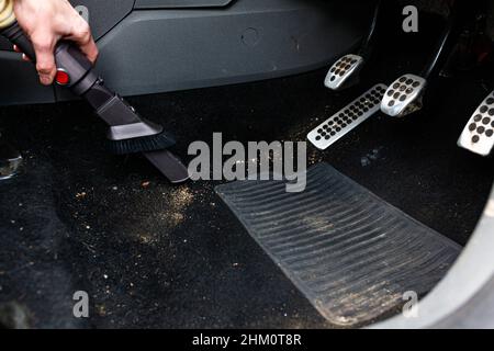Nahaufnahme einer unbekannten Person, die den Schmutz und Müll in ihrem Auto saugt Stockfoto