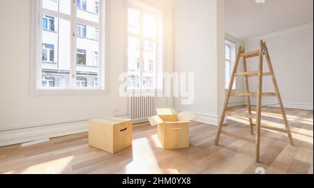 Umzugskisten im leeren Raum mit Leiter als Umzugsbild oder Speditionskonzept Stockfoto