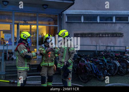 Berlin, Deutschland. 06th. Februar 2022. Feuerwehrleute stehen vor einem Heim für Obdachlose. Im Untergeschoss des mehrstöckigen Gebäudes war ein Feuer ausgebrochen. Nach Angaben eines Sprechers ist es der Feuerwehr gelungen, den Brand relativ schnell zu löschen. Quelle: Carsten Koall/dpa/Alamy Live News Stockfoto