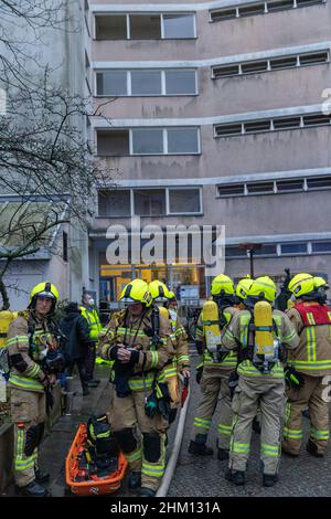 Berlin, Deutschland. 06th. Februar 2022. Feuerwehrleute stehen vor einem Heim für Obdachlose. Im Untergeschoss des mehrstöckigen Gebäudes war ein Feuer ausgebrochen. Nach Angaben eines Sprechers ist es der Feuerwehr gelungen, den Brand relativ schnell zu löschen. Quelle: Carsten Koall/dpa/Alamy Live News Stockfoto