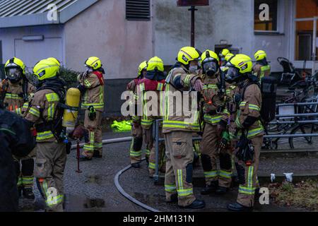 Berlin, Deutschland. 06th. Februar 2022. Feuerwehrleute stehen vor einem Heim für Obdachlose. Im Untergeschoss des mehrstöckigen Gebäudes war ein Feuer ausgebrochen. Nach Angaben eines Sprechers ist es der Feuerwehr gelungen, den Brand relativ schnell zu löschen. Quelle: Carsten Koall/dpa/Alamy Live News Stockfoto