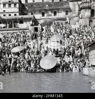 1950s, historische, Hindus versammeln sich an den steilen Ufern des Ganges, Benares (Varanasi), Indien, als Teil einer religiösen Wallfahrt in der alten Stadt, eine der ältesten ständig bewohnten Städte der Welt. Die Gewässer des Ganges gelten in der hinduistischen Religion als heilig und sind ein Ort der Anbetung und der Trauer während der Wallfahrt. Stockfoto