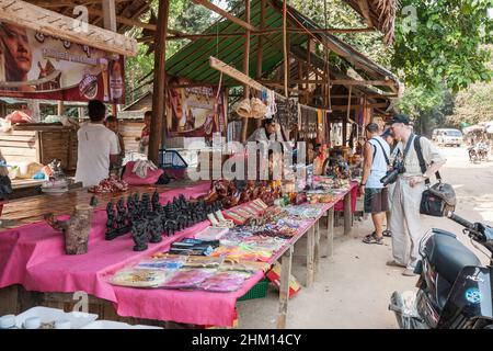 Phnom Kulen, Kambodscha - Februar, 2013: Touristen wählen Geschenke und Souvenirs auf einem Straßenmarkt in der Nähe lokaler Attraktionen im Phnom Kulen Nationalpark Stockfoto