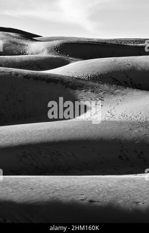 Schwarze und weiße Sanddüne mit Fußabdrücken, Himmel und Wolke am Morgen Stockfoto